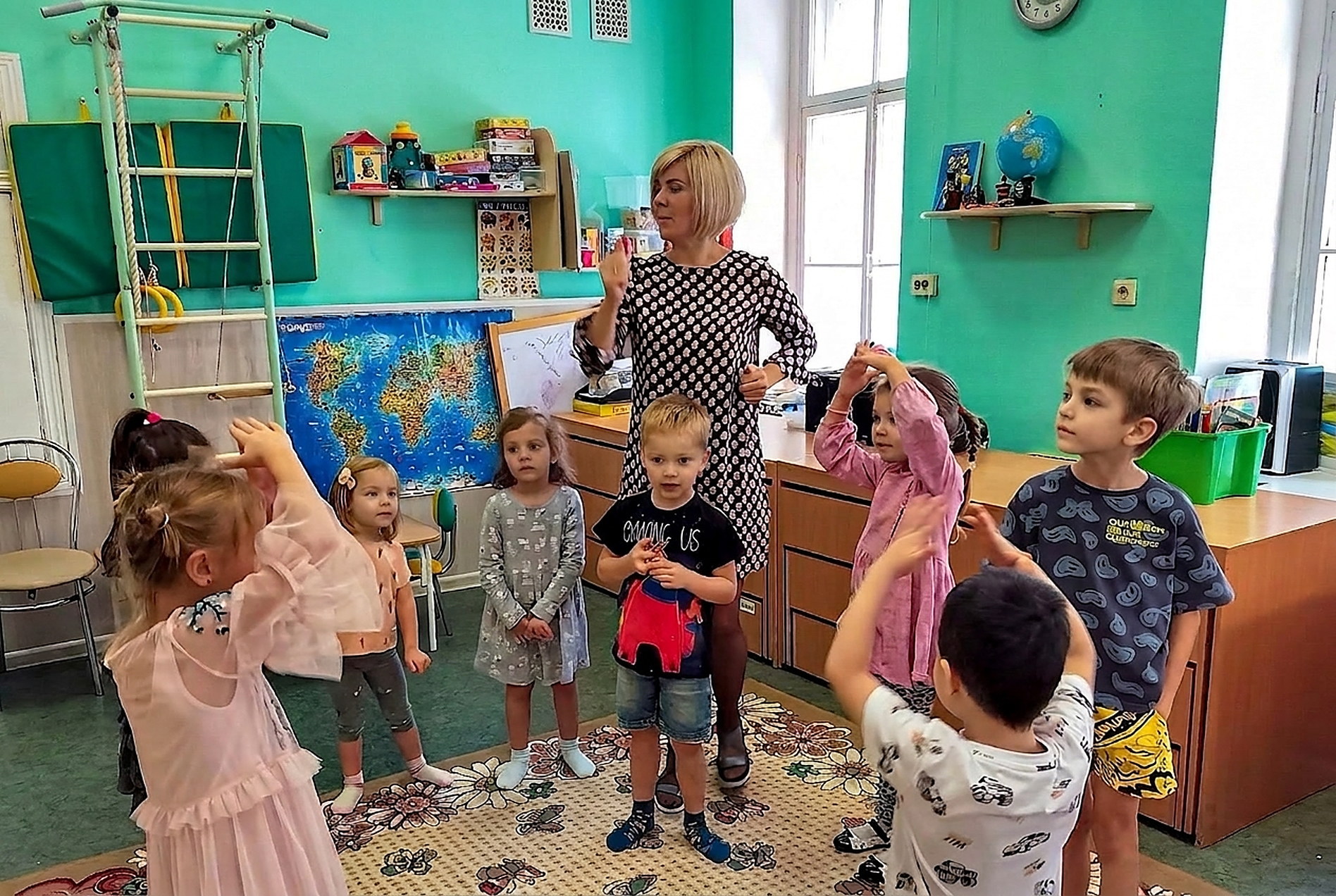 Педагог и дети разного возраста на общем занятии в группе